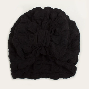 Macro detail of black bubble fabric baby turban with a large decorative bow