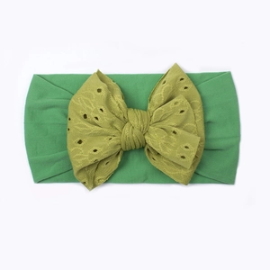 Dettaglio fascia per neonati in nylon con fiocco a strati e ricamo traforato verde