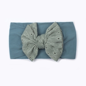 Dettaglio fascia neonato in nylon con fiocco in pizzo nei colori blu e verde grigio