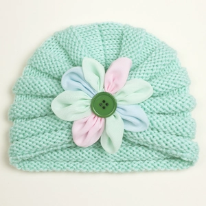 Detail of mint green baby knit hat with large colorful fabric flower and button