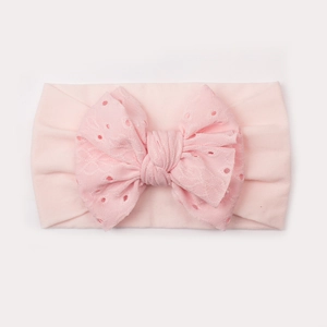 Dettaglio della fascia elastica rosa per neonata con fiocco in pizzo traforato fine