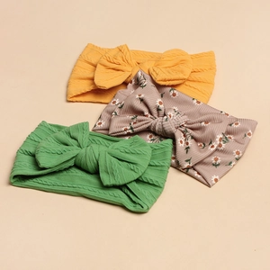 Set of three baby headbands featuring mustard yellow and green knit bows with daisy patterns