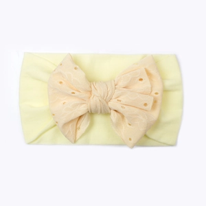 Dettaglio fascia per neonati in nylon con grande fiocco in pizzo traforato giallo chiaro