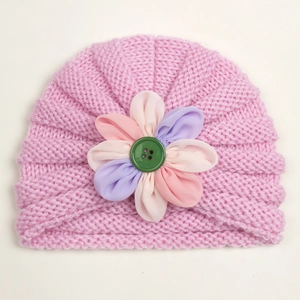 Pink knit baby turban hat with colorful fabric flower and green button detail