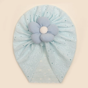Detail of baby hat with light blue lace texture and large striped flower ornament
