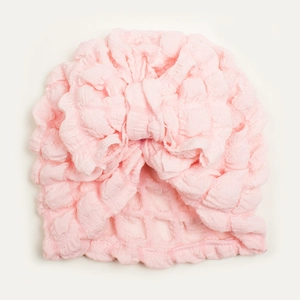 Close-up of light pink popcorn fabric baby turban with a large decorative bow