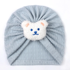 Detail of baby cable knit turban hat in light blue with white plush bear applique