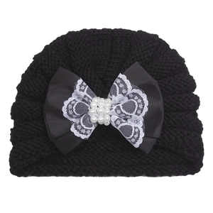 Detail of baby winter hat featuring a black bow with white lace and pearl cluster