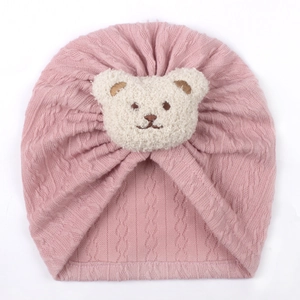 Close-up of pink cable knit baby hat featuring a cute white plush bear embroidery