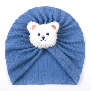 Detailed knit texture of blue baby hat with a plush bear face patch and embroidery