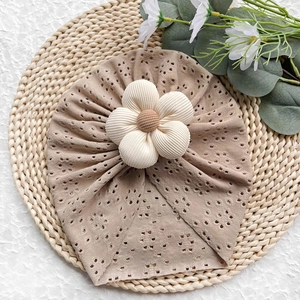 Dettaglio cappello neonato traforato con grande fiore in tessuto 3D e bottone marrone