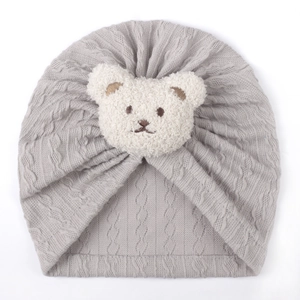Detail view of grey knit baby turban hat featuring a 3D plush bear and soft cable texture