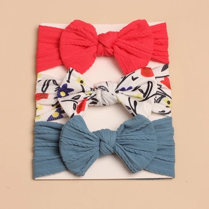 Detail of baby bow headbands in red, floral print, and blue with soft ribbed knit texture