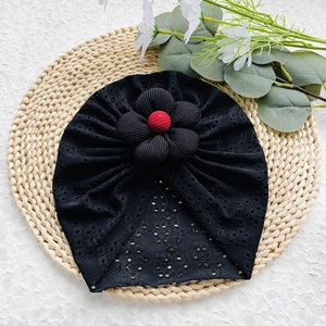 Dettaglio del turbante nero per neonato con trama traforata e grande fiore decorativo