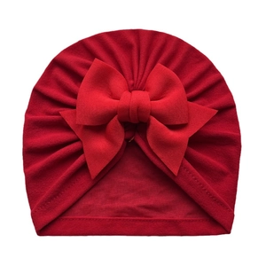 Détail d'un bonnet turban rouge pour bébé avec grand nœud et tissu en coton plissé