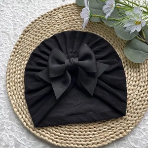Vue détaillée du bonnet turban noir pour nouveau-né en maille douce avec grand nœud