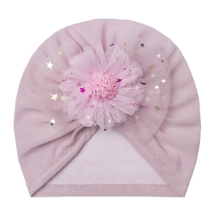 Detail of baby turban hat showing a large mesh flower with gold and purple star sequins
