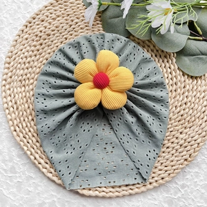 Dettaglio cappello neonato in maglia traforata verde salvia con fiore giallo in velluto