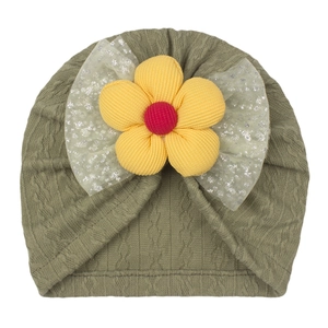 Detail of olive green knit turban hat featuring a yellow plush flower and sequined mesh bow