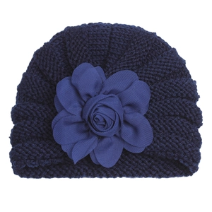 Gros plan sur un bonnet tricoté bleu marine pour bébé avec une grande fleur en tissu texturé