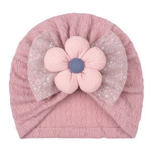 Detail of baby turban with pink knit texture and glitter mesh bow with floral deco