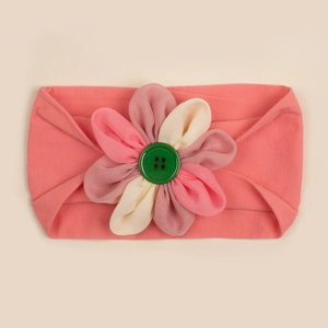 Dettaglio della fascia rosa in nylon per neonati con fiore in tessuto colorato e bottone