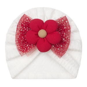 Close-up of white baby knit hat with red fabric flower and glittery mesh bow detail