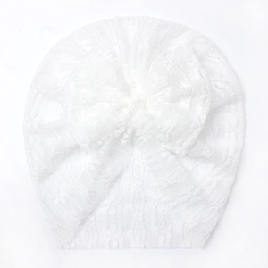 Dettaglio del cappellino in pizzo bianco per neonati con grande fiocco e trafori