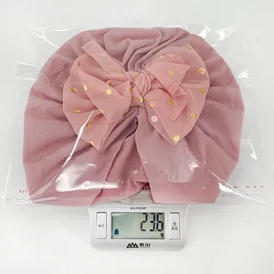 Dettaglio cappello turban rosa per neonata con fiocco a pois dorati, peso di 23,6 g
