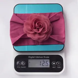 Detail view of 12.5g lightweight soft flower headband for infants on an electronic scale