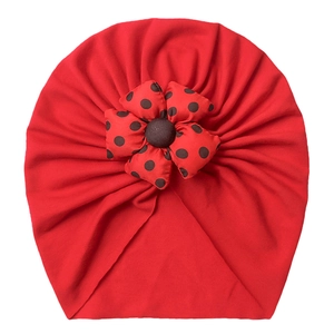 Detailed close-up of a red baby turban hat featuring a 3D polka dot fabric flower ornament