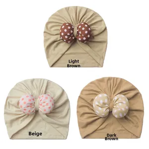 Detailed view of baby turban hats with polka dot bows in coffee and beige tones