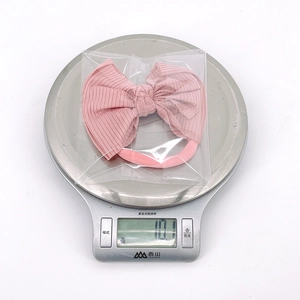 Bandeau bébé rose avec nœud tricoté pesant 10,1g sur une balance numérique