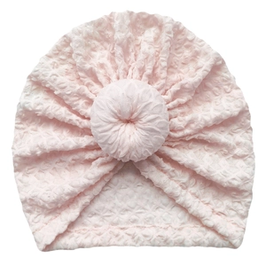 Close-up of light pink baby donut turban hat with bubble jacquard texture and soft knot