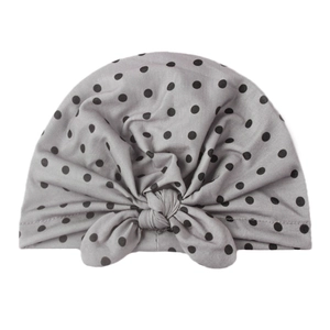 Gros plan détaillé du bonnet turban gris pour bébé avec pois noirs et nœud élégant