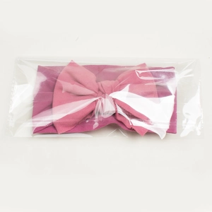 Detail view of pink bow nylon baby headband in clear plastic protective packaging