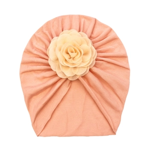 Detail of baby turban hat in lotus pink with cream fabric rose and soft knit texture
