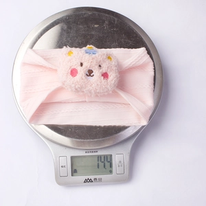 Pink ribbed knit baby headband with plush bear detail weighing 14.4g on a scale