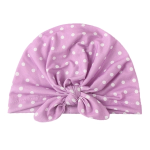 Détail du bonnet turban bébé violet à pois montrant le tissu tricoté et le nœud papillon