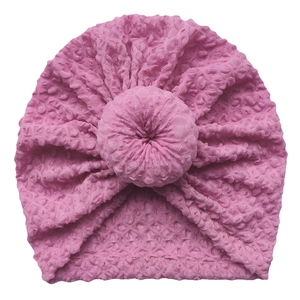 Detailed macro view of the pink baby donut hat showing soft bubble textured knit fabric