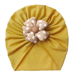 Detail of soft yellow baby turban hat with polka dot flower and ribbed cotton texture