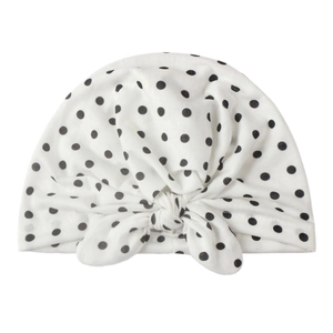 Détail du bonnet turban pour bébé en tissu blanc à pois noirs avec nœud sur le devant