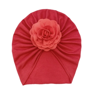 Close-up of red soft knit baby turban hat with large decorative 3D rose flower detail