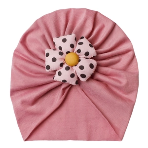 Detail of baby turban cap with handmade pink polka dot floral decoration in soft cotton