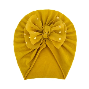 Dettaglio cappello neonato giallo senape con grande fiocco in organza a pois dorati