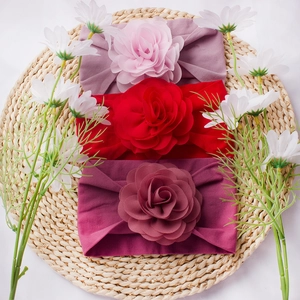 Three-piece infant flower headbands in pink and red on a rustic woven mat background