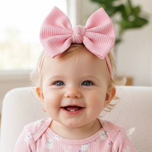Bandeau élastique rose à côtes pour bébés avec un grand nœud décoratif sur un nourrisson