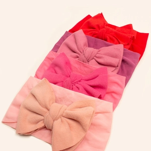 Detailed flat lay of soft nylon baby headbands with oversized bows in five different colors