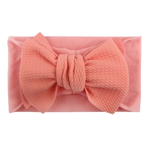 Dettaglio fascia neonata rosa in nylon con trama a nido d'ape e fiocco grande