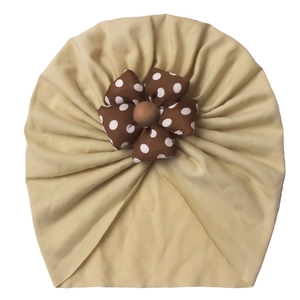 Detail of baby turban in beige with a brown polka dot flower and soft elastic fabric